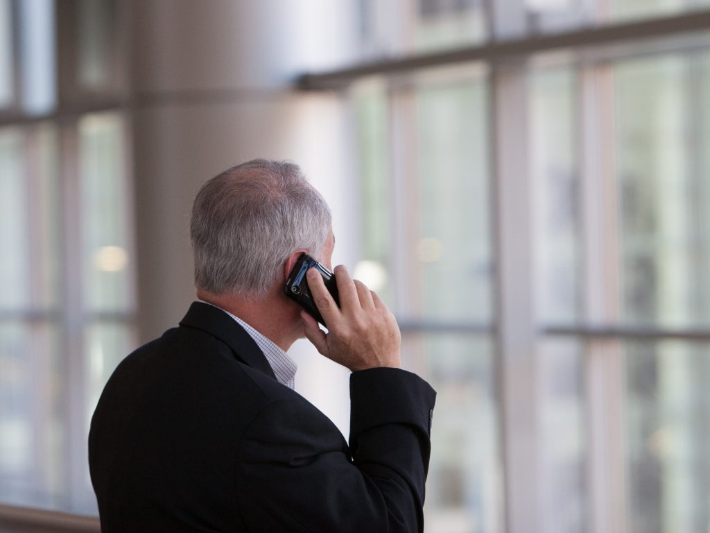 Man on Mobile Phone in front of window